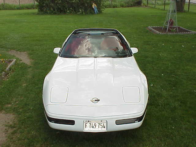 White 1994 Chevrolet Corvette parked on grass with a windmill in the background