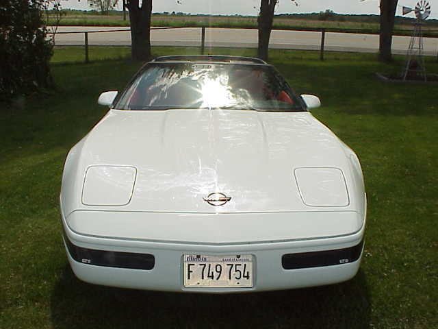 White 1994 Chevrolet Corvette with pop-up headlights down, parked on grass