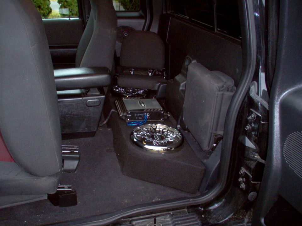 Truck interior showing custom subwoofer box and amplifier installed between the seats