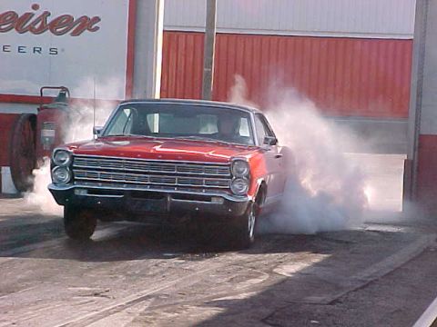 1967 Ford Galaxie - A red 1967 Ford Galaxie performs a burnout, kicking up a large cloud of smoke.