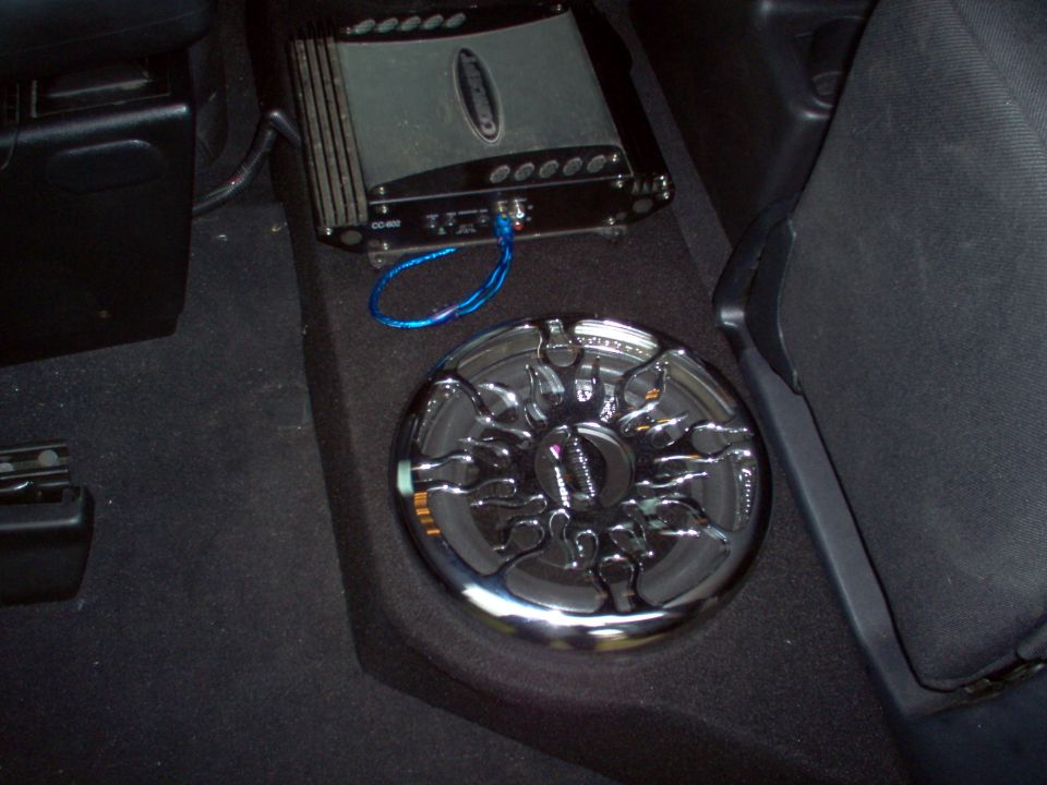 Car audio amplifier and chrome subwoofer installed in vehicle interior