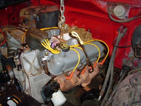1981 Ford Bronco - Engine assembly being lifted, showing spark plug wires and oil filter.