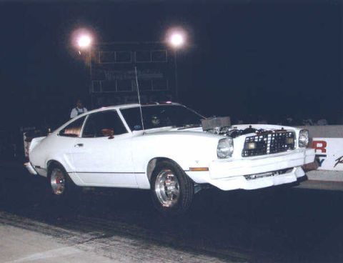 1976 Ford Mustang II - A modified 1975 Ford Mustang II is shown at a drag strip with its front wheels lifted during a race.