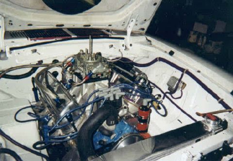 1976 Ford Mustang II - The engine bay of a 1976 Ford Mustang II shows a V8 engine with a prominent carburetor and custom wiring.