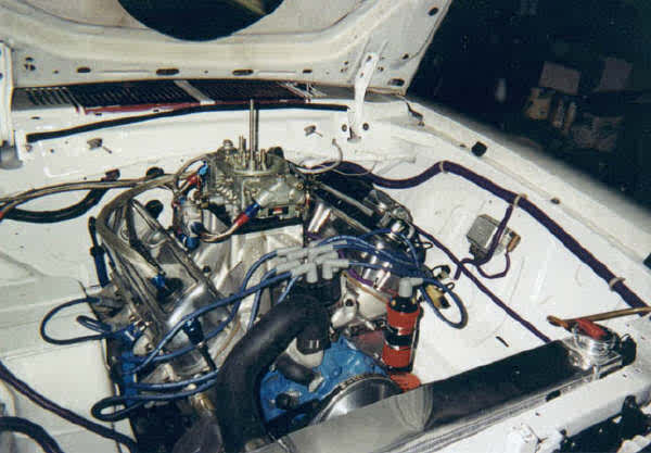 Engine bay of a 1976 Ford Mustang II with a V8 engine, carburetor, and custom wiring