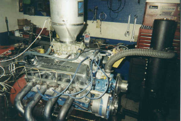 V8 engine with a large air intake and carburetor, exhaust headers, and alternator