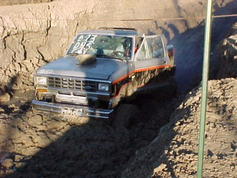 1987 Ford Ranger - A 1987 Ford Ranger truck is stuck in a muddy ditch, its front end visible.