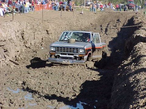 1987 Ford Ranger - A 1987 Ford Ranger navigates a muddy track during an event, with a crowd watching from the sidelines.