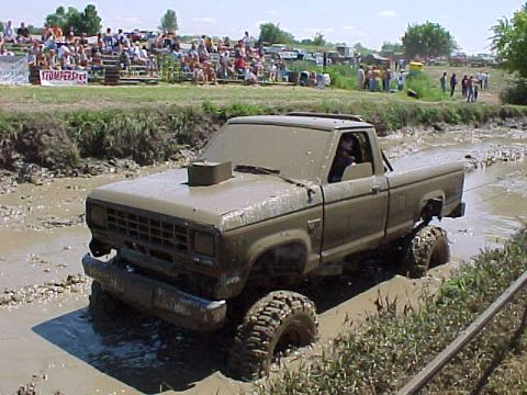 1987 Ford Ranger - A 1987 Ford Ranger navigates a muddy track during an event, with spectators in the background.