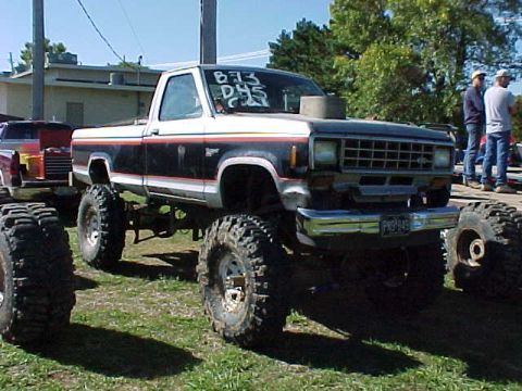 1987 Ford Ranger - A lifted 1987 Ford Ranger pickup truck with oversized tires is parked outdoors next to another vehicle.