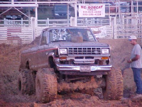 1987 Ford Ranger - A Ford Ranger is stuck deep in the mud at an event, with a man watching.