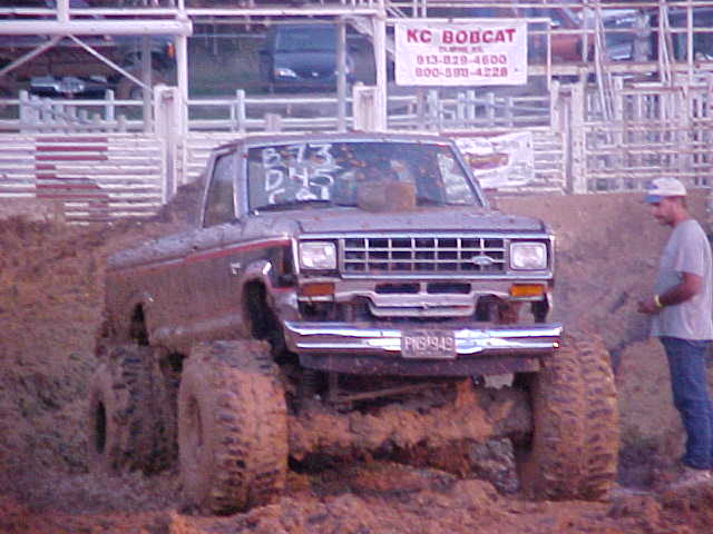 1987 Ford Ranger stuck in mud, driver standing nearby