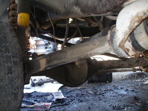 1993 Ford Bronco - Undercarriage view of a vehicle's front axle and suspension system, including the differential and a tire.