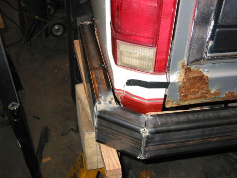 1985 Ford Bronco - A custom metal bumper is being fabricated and attached to the rear of a vehicle, showing significant rust on the body panel.