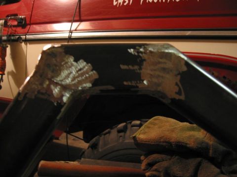 1985 Ford Bronco - Welding is being performed on a fender flare, with parts of a red vehicle and a tire visible.