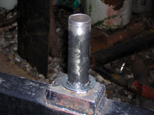 Threaded steel pipe nipple welded to a plate on a black square tube frame member
