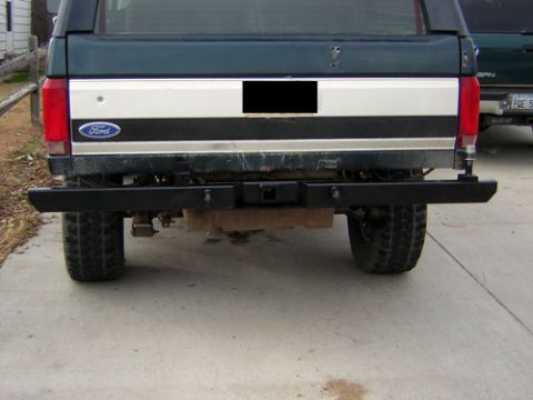 1995 Ford Bronco - Rear view of a dark green 1995 Ford Bronco, an aftermarket bumper and the iconic Ford tailgate stripe.