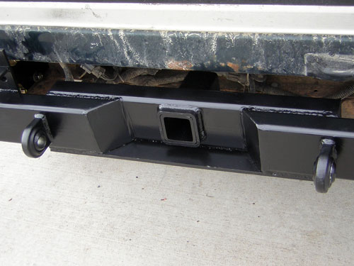 Black trailer hitch receiver mounted under a vehicle's rear frame