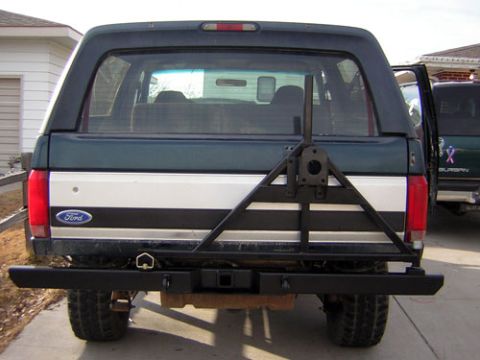 1995 Ford Bronco - Rear view of a Ford Bronco with a custom bumper and spare tire mount, parked next to another vehicle.