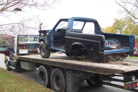 1989 Ford Bronco - A partially disassembled truck is being transported on a flatbed trailer, with another vehicle visible behind it.