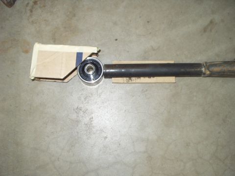 1993 Ford Bronco - A suspension component, possibly a control arm, with a bearing and makeshift cardboard protection, rests on a concrete floor.