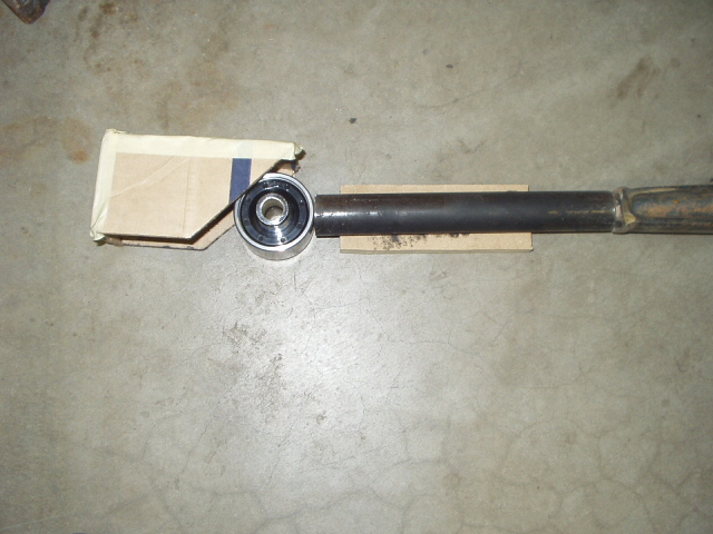 Suspension arm with large bushing bearing on cardboard, on concrete floor.