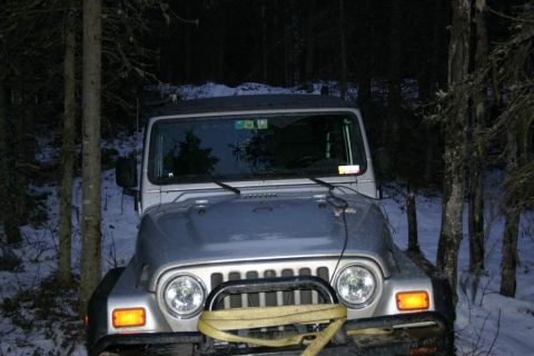 2003 Jeep TJ - A silver Jeep TJ is parked in a snowy forest at night, with a tow strap attached to the front.