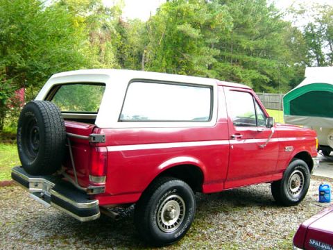 1988 Ford Bronco - This red Ford Bronco with a white removable top is viewed from the rear three-quarter angle.
