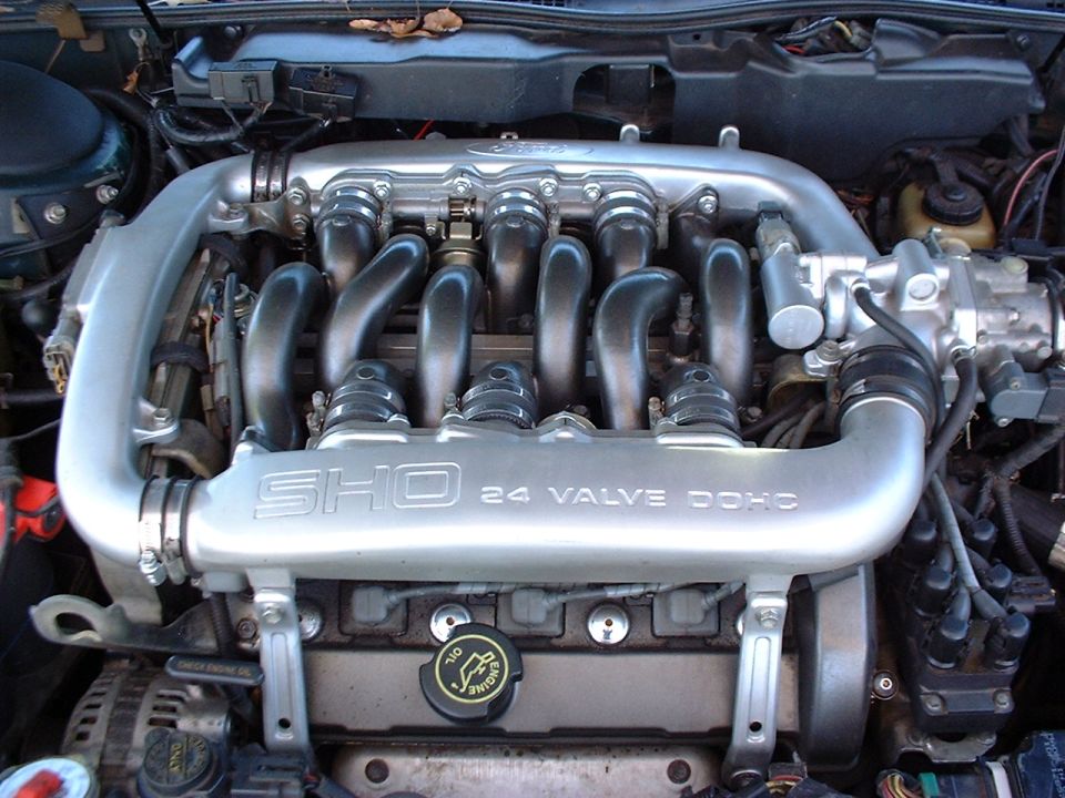 Engine bay with "SHO 24 VALVE DOHC" intake manifold. Oil cap visible