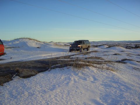 1996 Ford Bronco - Ford F-Series truck drives on a snow-covered road with a red vehicle on the left.