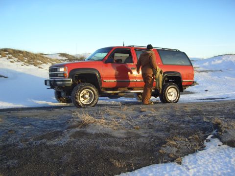 1996 Ford Bronco - A person exits a red SUV in a snowy, outdoor environment.