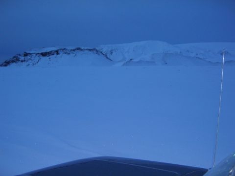 1996 Ford Bronco - Snowy landscape with mountains in background and the dark roof of a vehicle in the foreground.