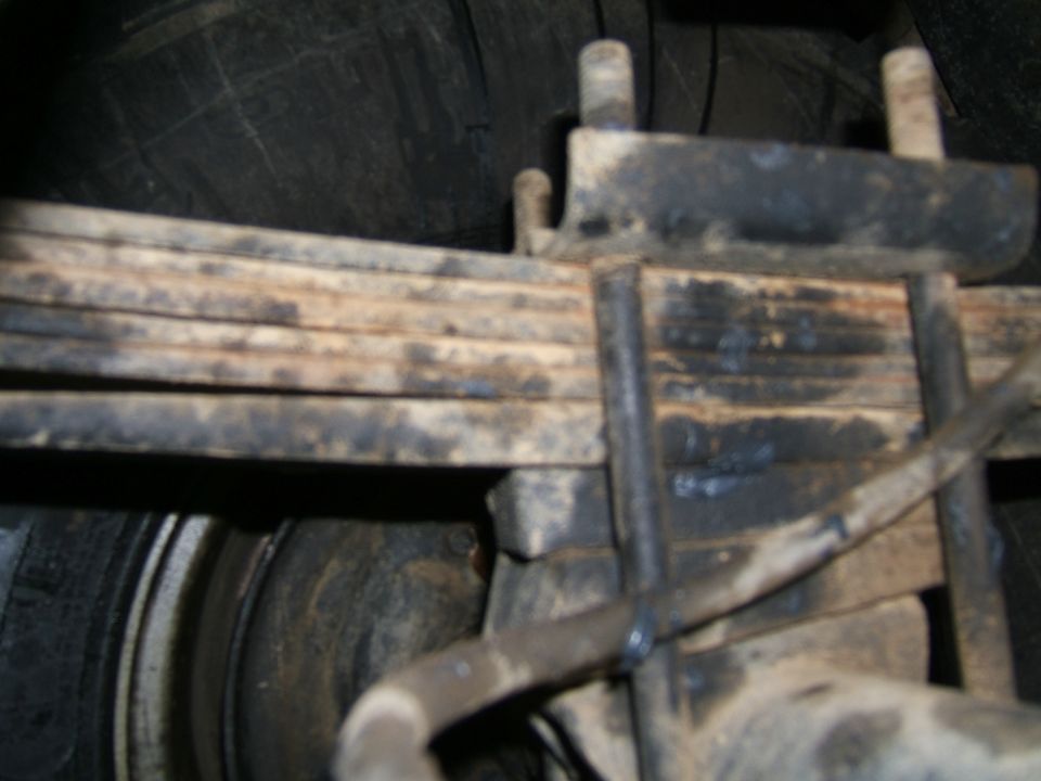 Close-up of a vehicle's leaf spring assembly and tire