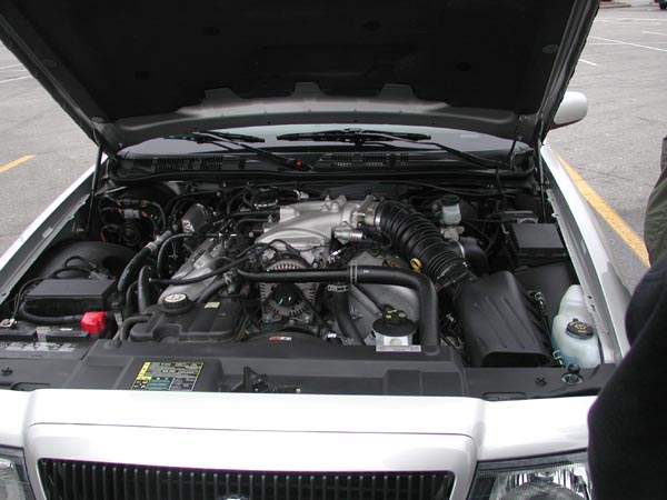engine bay of a silver car with hood open, showing engine components and air intake system