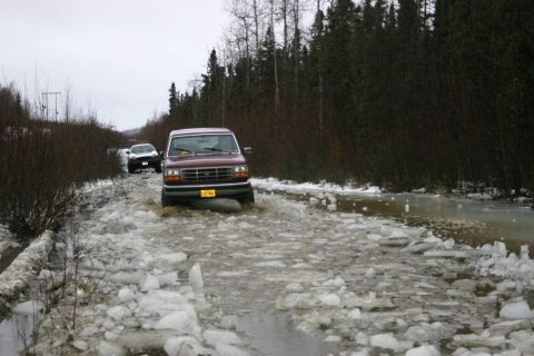 2003 Jeep TJ - A maroon SUV navigates a flooded, icy road with a white SUV following behind.