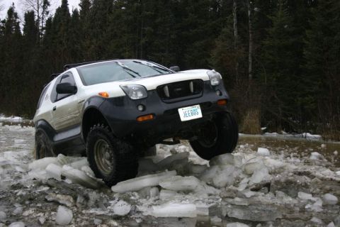 2003 Jeep TJ - This modified SUV navigates a challenging icy terrain, its license plate humorously reading 'JEEBUS'.