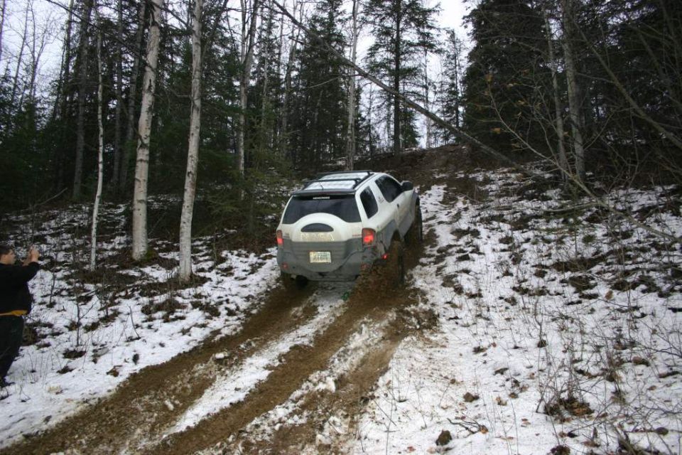 White SUV stuck in mud on a snowy hill, rear view
