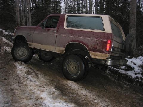 1993 Ford Bronco - This Ford Bronco is navigating a challenging off-road trail with snow and mud.