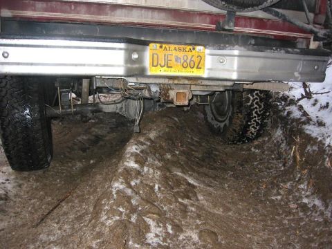 1993 Ford Bronco - The rear of a 1993 Ford Bronco is stuck in thick mud, with its tires partially submerged.