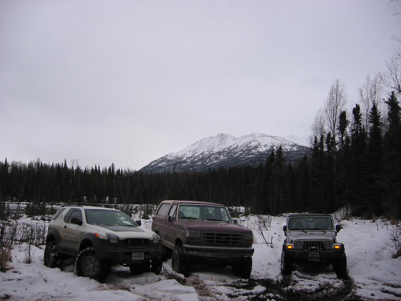 Maroon 1993 Ford Bronco parked in snow with two other SUVs, facing front