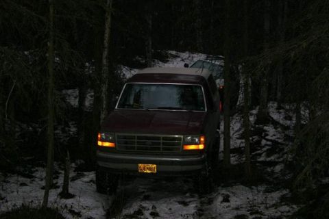 1993 Ford Bronco - A red SUV is parked in a snowy, wooded area, with another vehicle visible behind it.