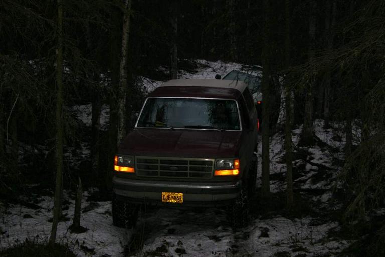 Red SUV with a grille that appears to be from the early 1990s, parked in a wooded area with snow on the ground