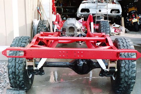 1976 Toyota Land Cruiser - Vehicle frame and suspension assembly, with other vehicles in the background.
