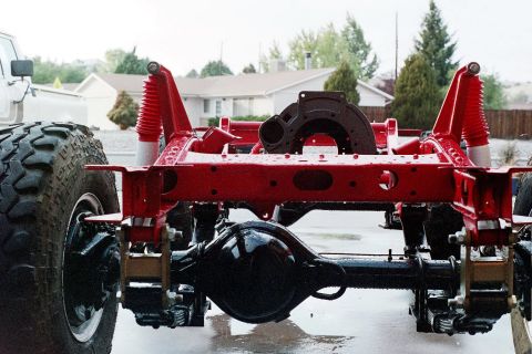 1976 Toyota Land Cruiser - The red painted frame and suspension components of a vehicle are visible, along with a large tire.