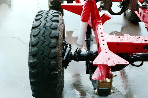 1976 Toyota Land Cruiser - Close-up of a large off-road tire and the red painted frame of a vehicle, likely during a rebuild.