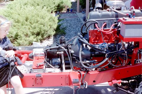 1976 Toyota Land Cruiser - A child is seen working on the chassis and engine of a vehicle during a rebuild.