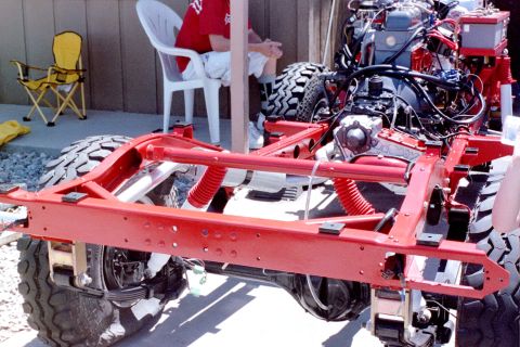1976 Toyota Land Cruiser - The chassis and engine of a vehicle undergoing reconstruction, with a person relaxing in the background.