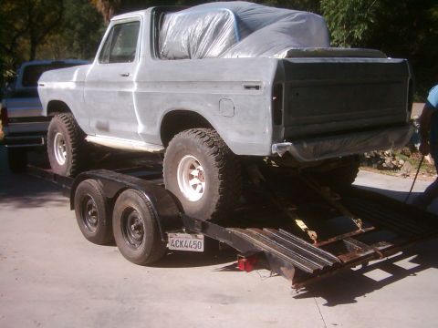 1978 Ford Bronco - A gray 1978 Ford Bronco is loaded onto a trailer, with its rear cargo area covered.