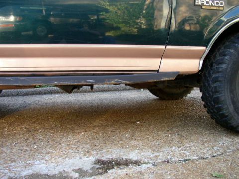 1995 Ford Bronco - Side view of a 1995 Ford Bronco, showing its two-tone paint and a damaged running board.