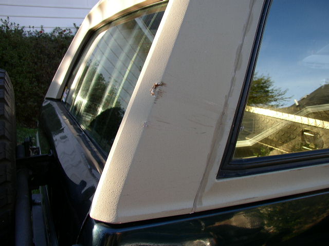 Dark green 1992 Ford Bronco rear quarter panel with a beige hardtop and a dent on the pillar